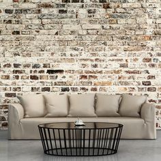 a white couch sitting in front of a brick wall next to a black coffee table