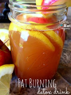 a mason jar filled with liquid and sliced apples on top of a table next to lemon wedges