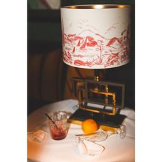 a lamp sitting on top of a table next to an orange and some other items