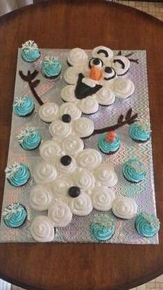 a cake made to look like a snowman with cupcakes on the table