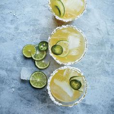 three margarita cocktails with lime slices and sugar on the rim, garnished with an avocado