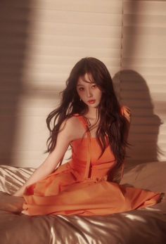 a woman in an orange dress sitting on a bed