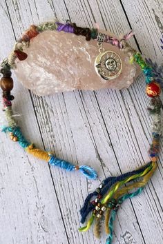 a bracelet with beads and charms on it sitting on a white wooden table next to a potted plant