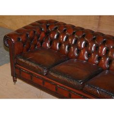 a brown leather couch sitting on top of a wooden floor