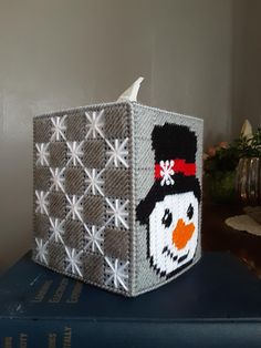 a knitted box sitting on top of a blue book