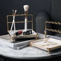 a marble table topped with two trays filled with makeup brushes and other personal care items