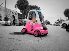 a baby is sitting in a pink toy car