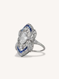 a white gold ring with blue and white stones on it's center, surrounded by diamonds