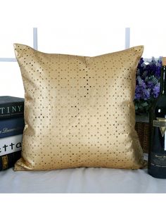 a gold pillow sitting on top of a table next to bottles of wine and books