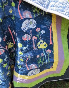 a quilted jacket with trees and flowers on it, sitting in the middle of grass