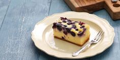 a piece of blueberry cheesecake on a plate next to a knife and fork