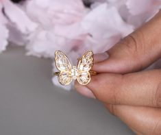 a woman's hand holding a gold butterfly ring