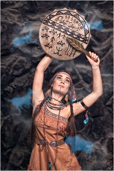 a woman in native dress holding up a wooden bowl