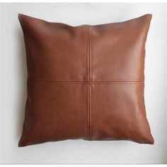 a brown leather pillow sitting on top of a white wall