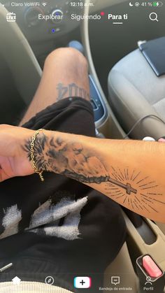 a person with tattoos on their arm sitting in a car