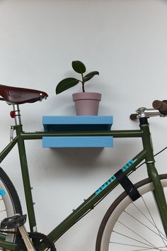 a green bike parked next to a wall with a plant on top of the rack