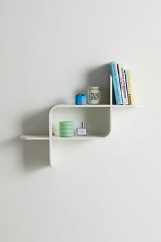 two white shelves on the wall with books and other items sitting on top of them