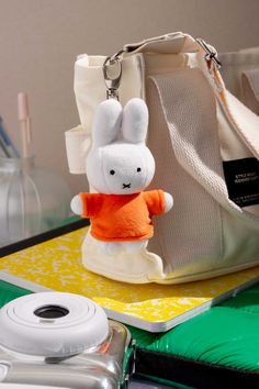 a white rabbit keychain sitting on top of a table next to a camera