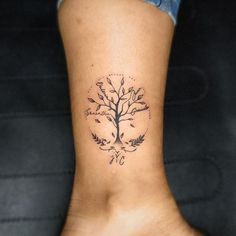 a woman's foot with a small tree tattoo on the back of her leg