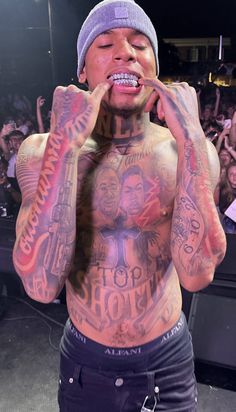 a man with tattoos on his chest and hands in front of him, covering his mouth