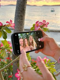 a woman taking a photo with her cell phone while standing in front of some flowers