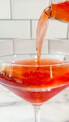 a glass filled with liquid sitting on top of a counter next to a white tile wall