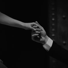 black and white photograph of two people holding each other's hands in the air