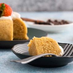 a piece of cake on a plate with a fork next to it and a bowl of strawberries in the background