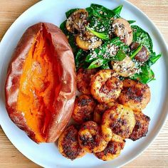 a white plate topped with meat and veggies on top of a wooden table