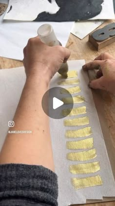 a person is painting on paper with yellow paint