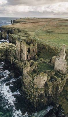 an aerial view of the cliffs and ocean near a rocky cliff with grass growing on it