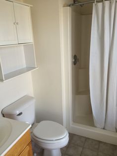 a white toilet sitting next to a bath tub in a bathroom under a shower curtain