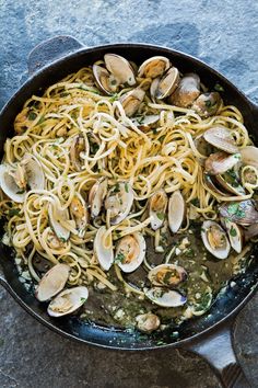 pasta with clams and sauce in a skillet on a stone counter top, ready to be eaten