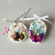 two ceramic ornaments with flowers on them are tied to a ribbon and placed next to each other