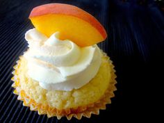 a cupcake topped with whipped cream and an orange slice on top is sitting on a black surface