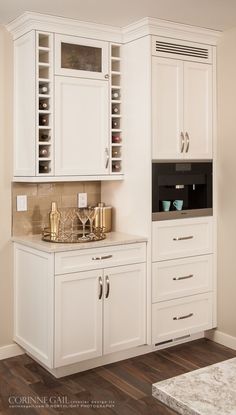 a kitchen with white cabinets and gold accents