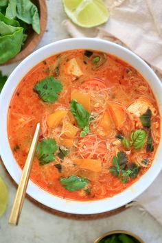 a white bowl filled with soup and garnished with cilantro, parsley and lime