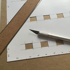 a pen sitting on top of a piece of paper next to a ruler with holes in it