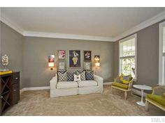 a living room with two couches, chairs and pictures on the wall above them