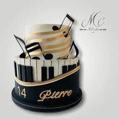 a black and white cake with musical notes on it's top, topped with gold ribbon