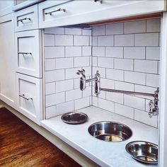 two stainless steel bowls in the corner of a white kitchen countertop with matching sinks