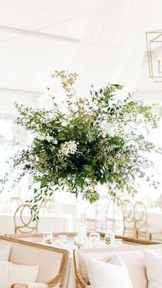 a vase filled with greenery sitting on top of a table next to white couches