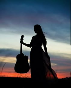 the silhouette of a woman holding a guitar in front of an ornate frame at sunset