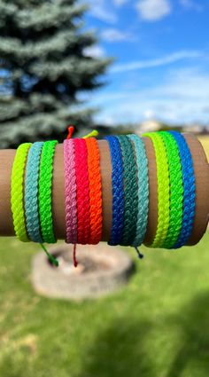 a person is holding several different colored bracelets on their arm and the other one has a red string attached to it