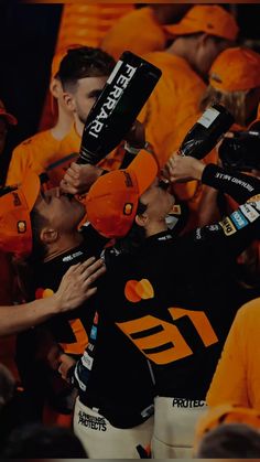 a group of men standing next to each other in front of a crowd holding up baseball bats