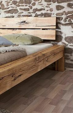 a bed with wooden slats and pillows on it in front of a stone wall