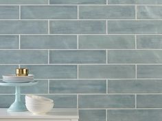 a white table topped with plates next to a blue wall covered in grey and white tiles