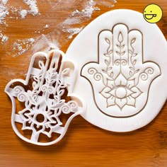 two cookie cutters with the design of a hamsa hand and snowflakes