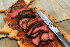 sliced steak on wooden cutting board with knife