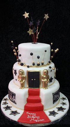 a three tiered cake with stars and decorations on the top is decorated in white, red, and gold